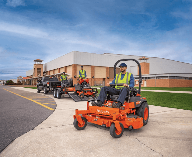 Landscaping crew riding mowers off of trailer