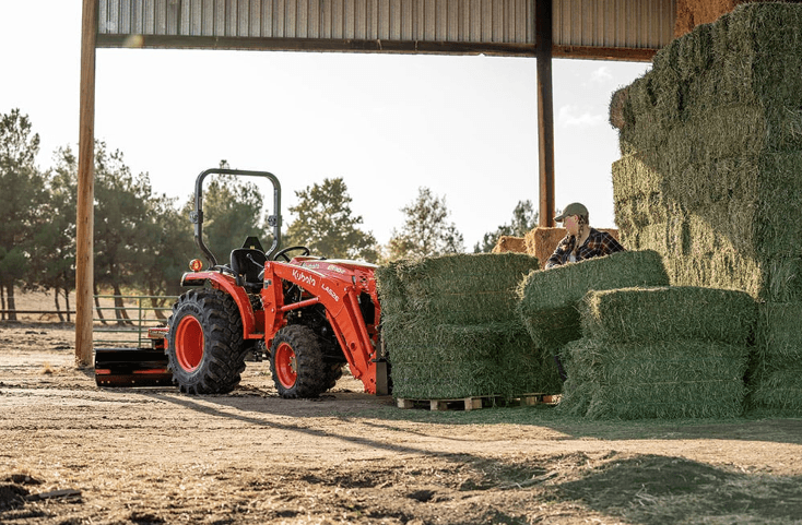 Woman loading hay stacks onto front end of tractor