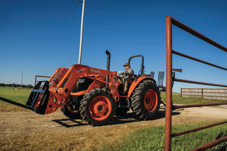 Man driving utility tractor through an open gate