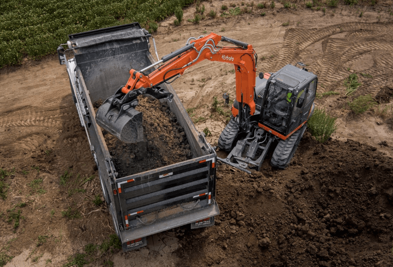 Excavator dumping dirt onto the back of truck