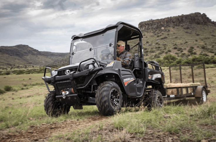 Man driving RTV with a trailer hitched to the back