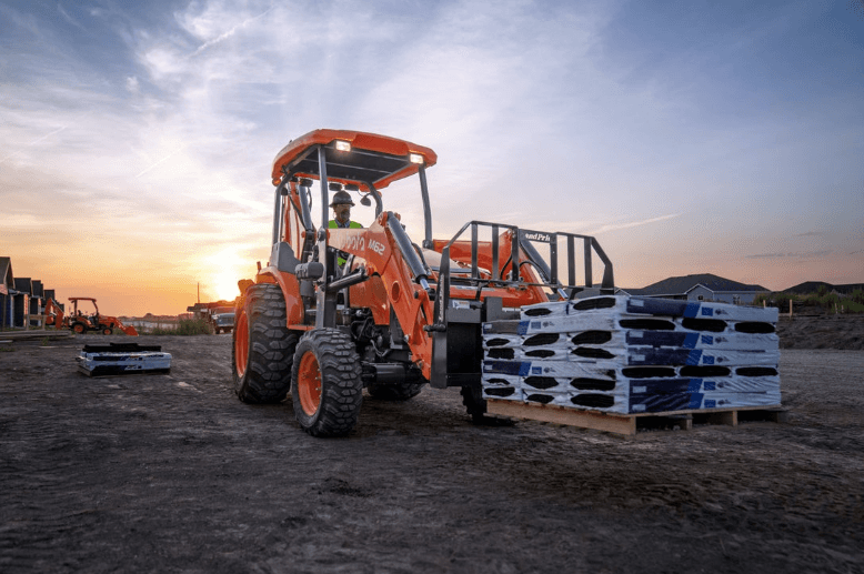 Tractor Loader Backhoe carrying a pallet of material